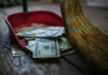 Trump Puts Bounty On Fraud Broom sweeping dollar bills into red dustpan floor