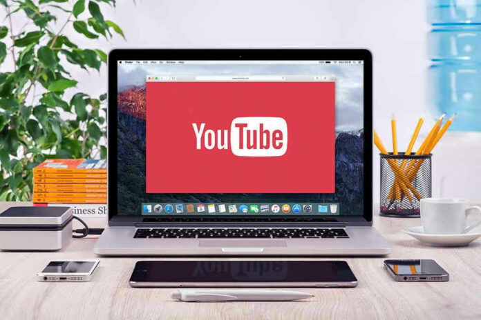 YouTube logo on a laptop screen on desk.