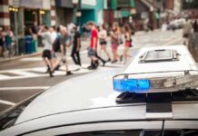 police car roof light bar with blue lights near a busy crosswalk
