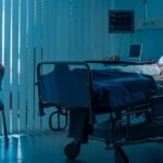 hospital room with child in bed and adult sitting nearby