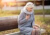 Older woman on park bench holding chest
