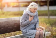 Older woman on park bench holding chest