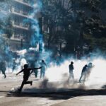 Protesters running through tear gas on a city street