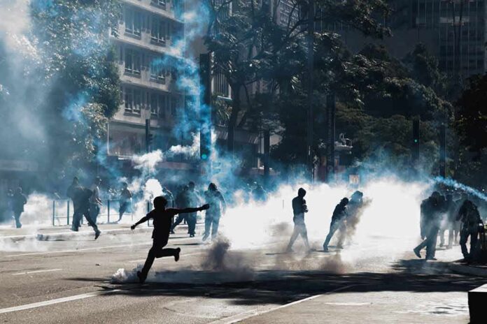 shutterstock_1747405187 Protesters running through tear gas on a city street