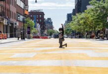 Midtown Stabbing Sparks Hate Crime Probe Person kneeling on painted city street raising fist