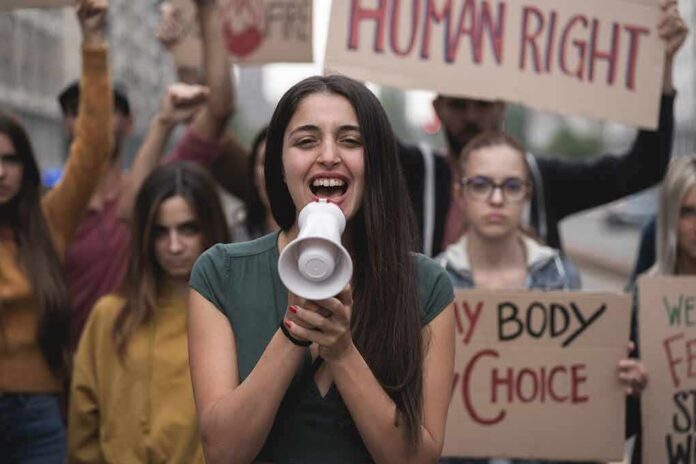 shutterstock_2059141274 Young woman leading a protest with a megaphone