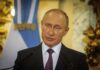 Vladimir Putin speaking at a podium with microphones