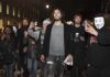 Russell Brand walking with a crowd at night