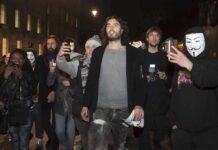Russell Brand walking with a crowd at night