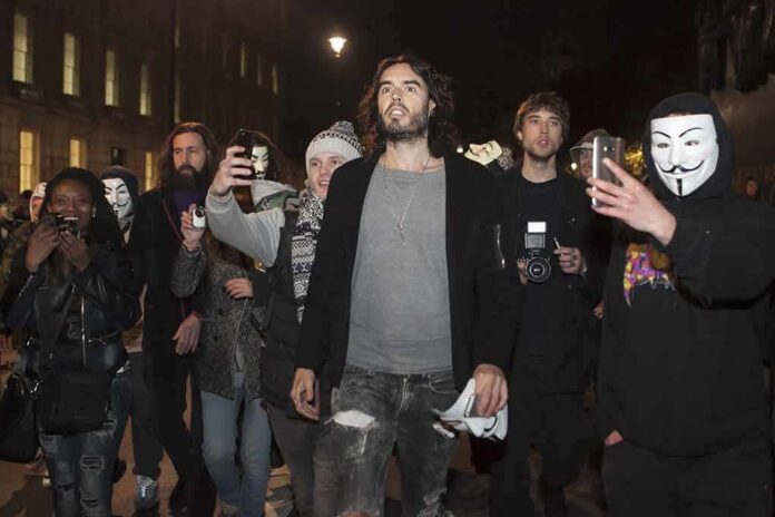 Russell Brand walking with a crowd at night