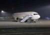 Passenger airplane parked on tarmac at night with mobile stairs
