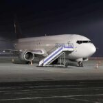Passenger airplane parked on tarmac at night with mobile stairs