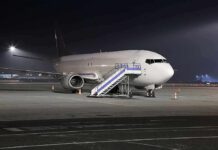 Passenger airplane parked on tarmac at night with mobile stairs
