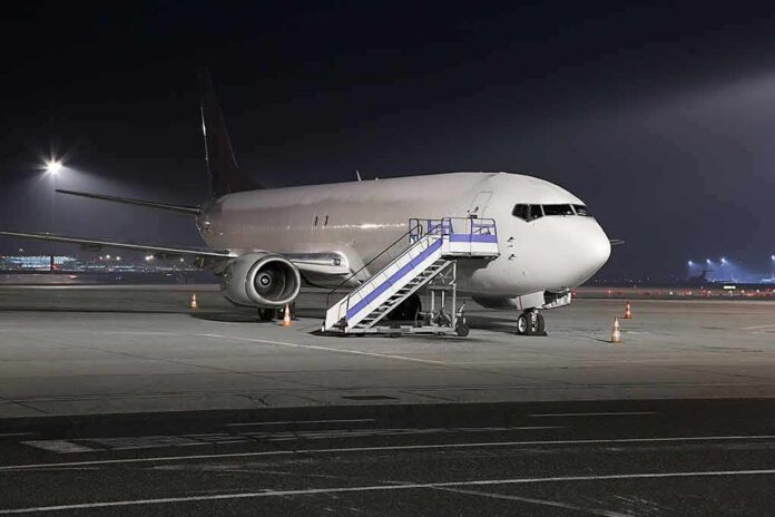 Passenger airplane parked on tarmac at night with mobile stairs