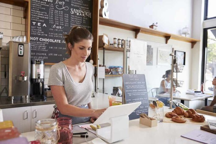 shutterstock_509238976 Barista using a tablet register at a cafe counter