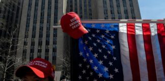 Man wearing red cap near American flag outdoors