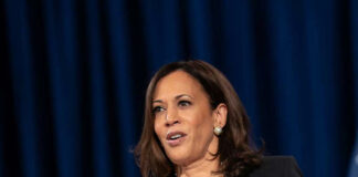Woman speaking at a podium with blue background.