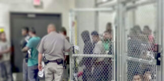 People detained behind fencing in a detention center.