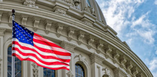 US flag waving in front of Capitol building.