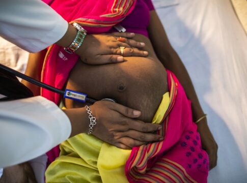 A healthcare professional examining a pregnant woman's abdomen with a stethoscope