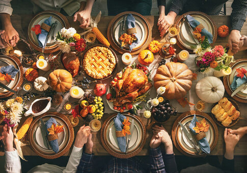 A beautifully arranged Thanksgiving dinner table with a turkey, pies, and autumn decorations