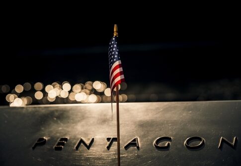 Close-up of a small American flag on a reflective surface with the word PENTAGON in the background