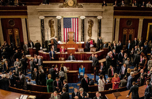 Large group in U.S. Congress chamber, American flag displayed.