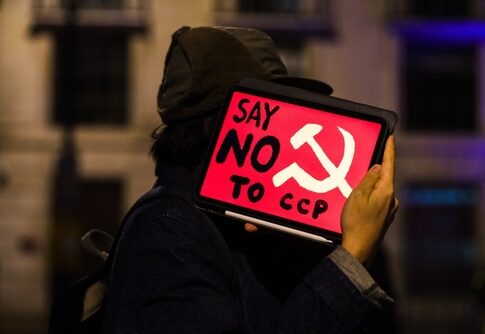 Person holding a protest sign that reads Say NO to CCP with a communist symbol