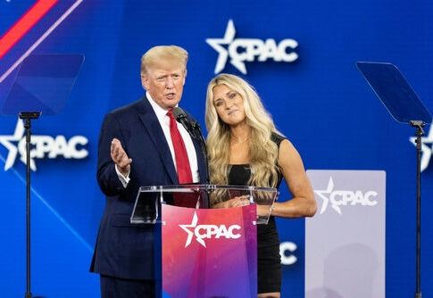 Two people speaking at CPAC event stage.
