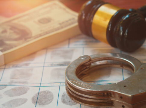 Handcuffs on fingerprint sheet with gavel and cash