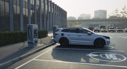 A silver electric vehicle charging at a station in a parking lot