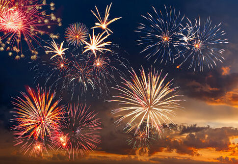 Colorful fireworks display against a darkening evening sky.
