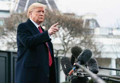 A man in a suit gesturing while speaking at a press conference outside the White House
